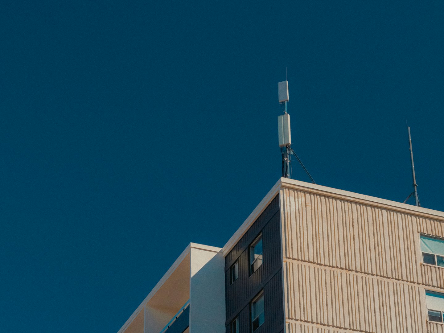 Modern building with communication antennas on its rooftop.